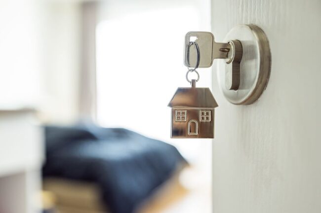 Open the door and door handle with a key and a keychain shaped house.