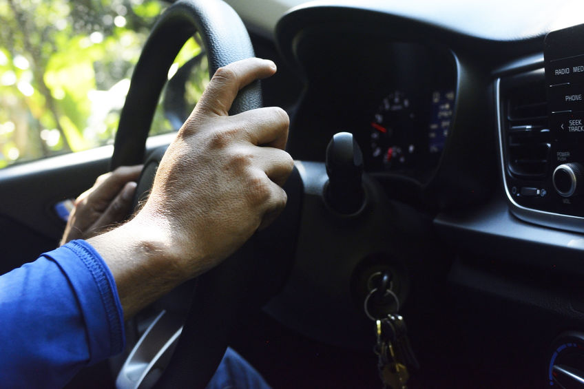 Man driving car with both hands on steering wheel